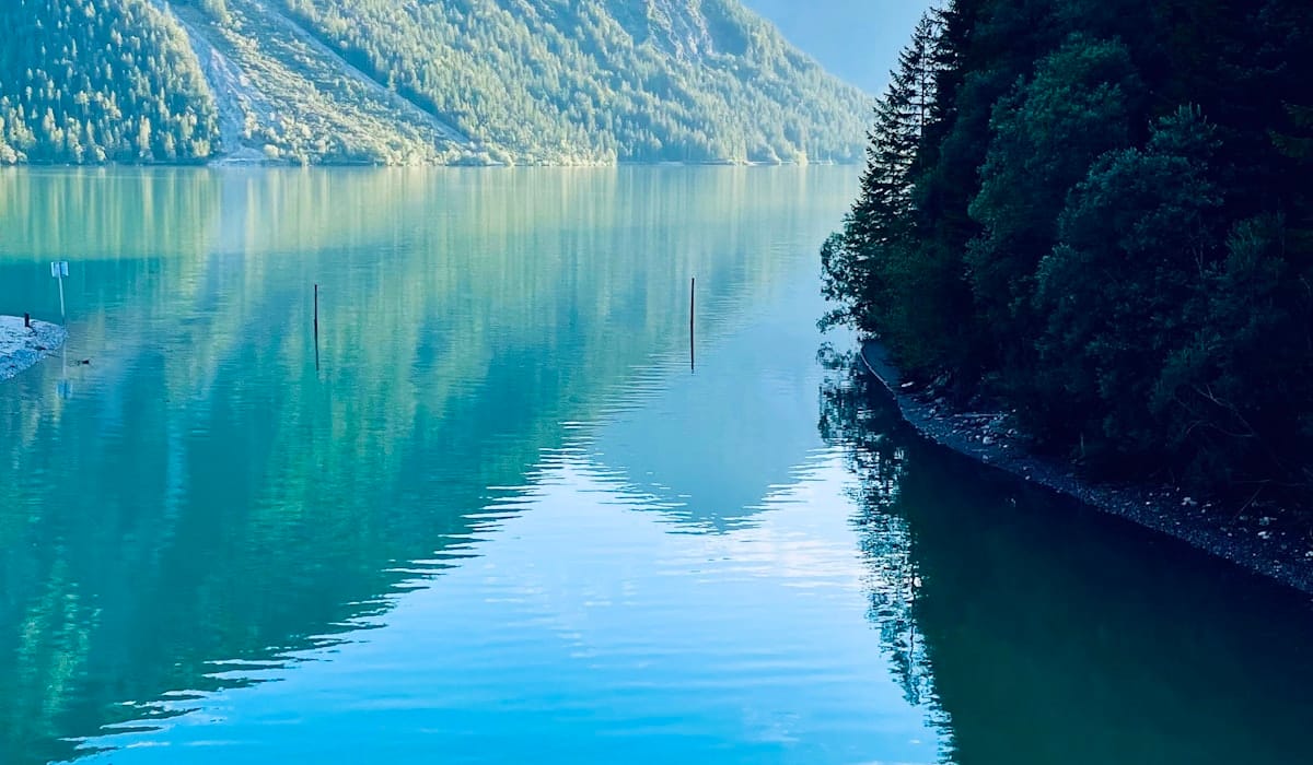 Personne pagayant en kayak seule sur un lac calme entouré de verdure